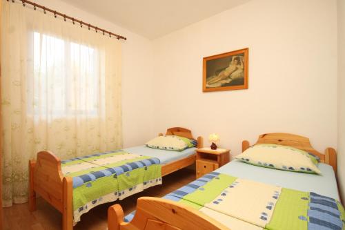 two twin beds in a room with a window at Apartments with a parking space Rukavac, Vis - 8836 in Vis