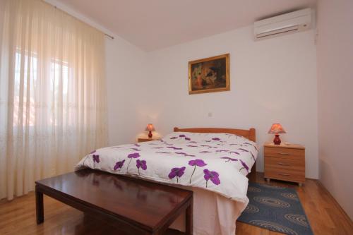 ein Schlafzimmer mit einem Bett mit lila Blumen darauf in der Unterkunft Apartments by the sea Sutomiscica, Ugljan - 8474 in Sutomišćica