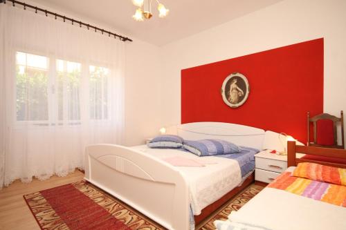 een slaapkamer met een wit bed en een rode muur bij Apartments by the sea Ugljan - 8266 in Ugljan
