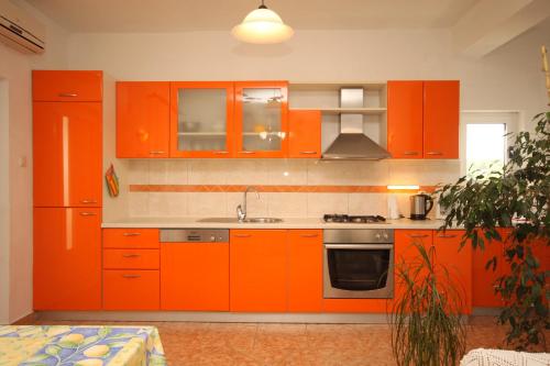 een keuken met oranje kasten en een wastafel bij Apartments by the sea Ugljan - 8266 in Ugljan