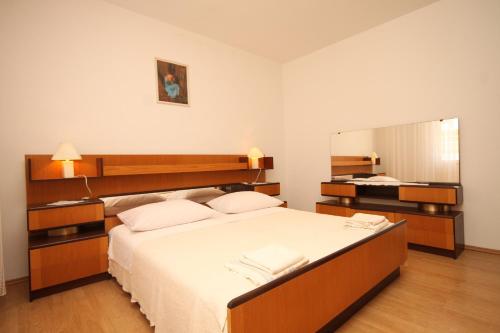 a bedroom with a large bed and a mirror at Apartment Kukljica 8237b in Kukljica