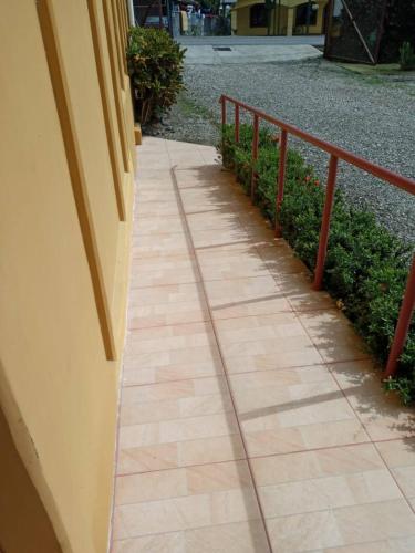 a sidewalk next to a building with a red railing at Hospedaje Poly in Río Claro