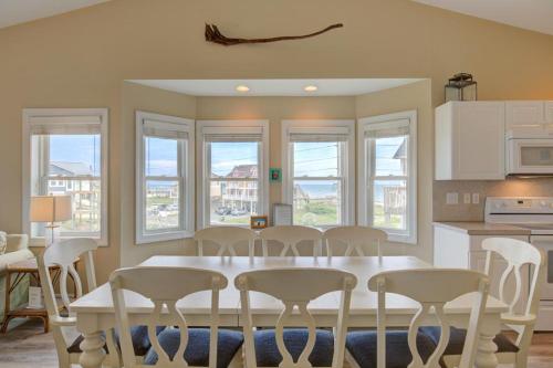 a kitchen with a white table and chairs and windows at Pinella Beach House in North Topsail Beach