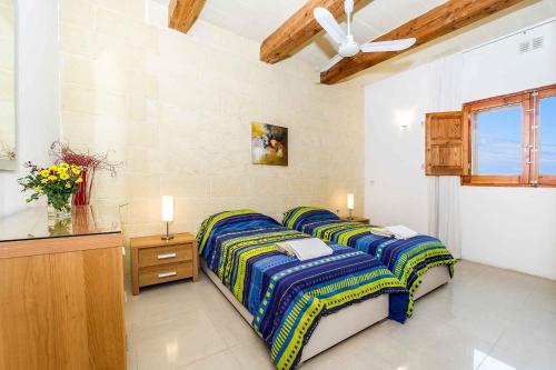 a bedroom with two beds and a dresser and a window at Four Winds Holiday Home in Kerċem