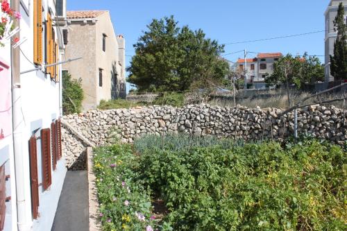 a stone wall next to a garden with flowers at Apartment Stivan 382a in Štivan