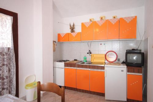 a kitchen with orange and white cabinets and a tv at Apartment Stivan 382a in Štivan