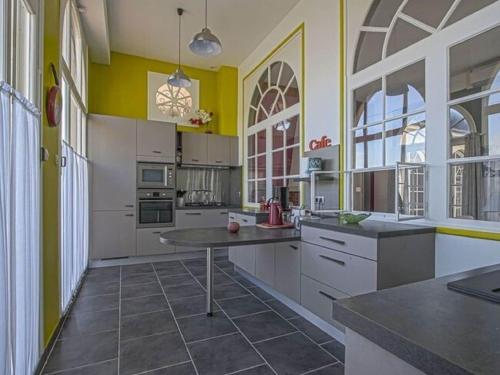 une grande cuisine avec des murs jaunes et des armoires blanches dans l'établissement Holiday Home in Bayeux near the Sea, à Sainte-Honorine-des-Pertes