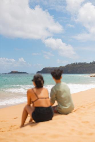 a man and a woman sitting on the beach at The Cliffs at Princeville in Princeville