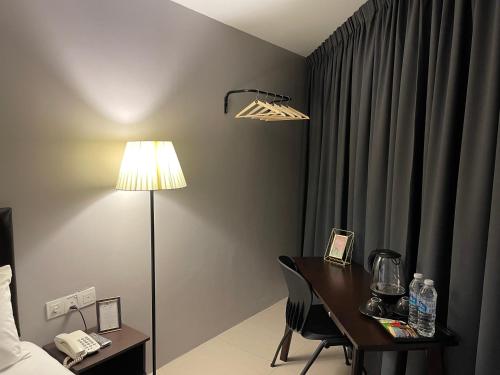 a room with a desk and a lamp and a bed at Royale City Hotel - 10 min from KLIA KLIA 2 Airport in Sepang
