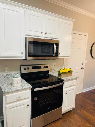 a kitchen with white cabinets and a black stove top oven at Stylish and Cozy Retreat in Buford