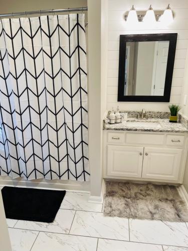 a bathroom with a sink and a shower with a mirror at Stylish and Cozy Retreat in Buford