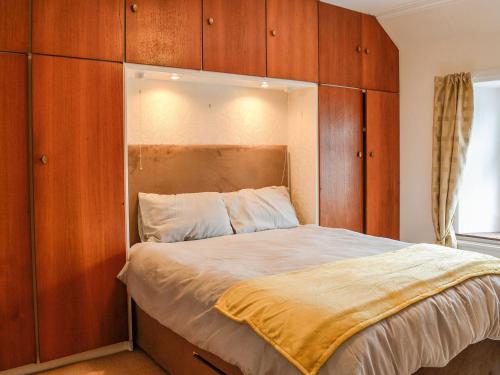 a bedroom with a large bed with wooden cabinets at The Moorings in Lochmaben