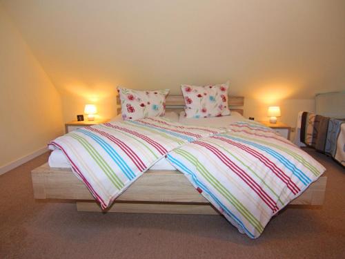een slaapkamer met een groot bed met kleurrijke dekens en kussens bij holiday home Strandloper, Zinnowitz in Zinnowitz
