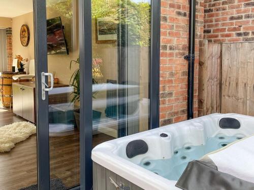 a bath tub in a room with a brick wall at Paddocks View in Breedon on the Hill