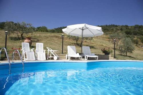 un grupo de sillas y una sombrilla junto a la piscina en Yurta con uso piscina e vista meravigliosa, en Dicomano