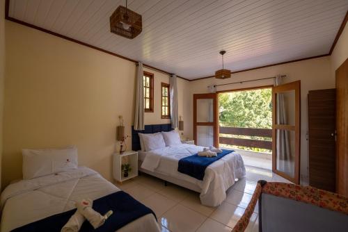 a bedroom with two beds and a large window at Casa Di Maria 4 Quartos a 500m Centro - Sauna, Piscina, Fogão a Lenha, Churrasqueira - ACESSO PRIVATIVO AO AO RIO - Ideal para famílias in Nova Friburgo