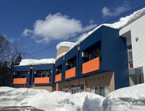 a building covered in snow next to a pile of snow at 松代棚田ハウス 