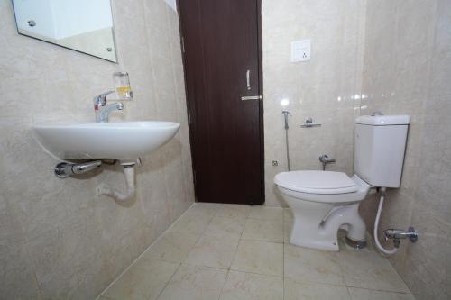 a bathroom with a white toilet and a sink at Comfort Stay in Faridabad