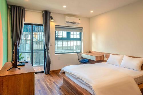 1 dormitorio con 1 cama, TV y ventana en POTA Hotel & Apartment, en Da Nang