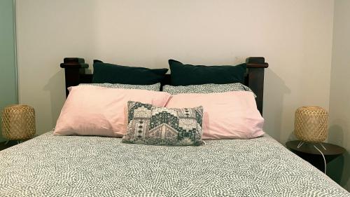uma cama com quatro almofadas em cima em Brand New PARK AVENUE Apartment in the Heart of Canberra City em Camberra