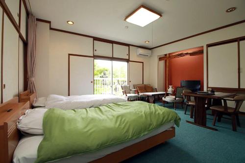 1 dormitorio con 1 cama, mesa y sillas en Takasago Onsen, en Asahikawa