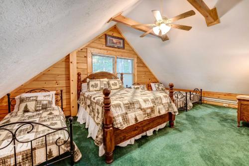 - une chambre avec 2 lits et un ventilateur de plafond dans l'établissement Waynesville Cabin with Covered Deck and Fire Pit!, à Lake Junaluska