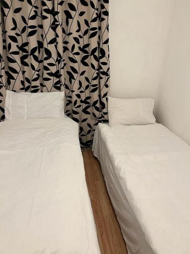 two beds sitting next to each other in a room at HAPPY HOURS HOME STAY in London