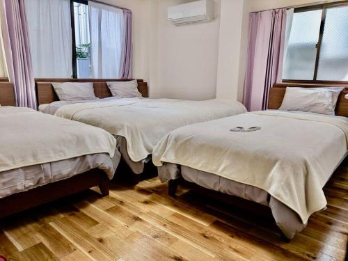two beds in a room with wooden floors and windows at Grato Terrace in Tokyo