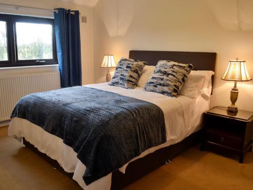 a bedroom with a large bed with two pillows at Angerton Cottage in Kirklinton