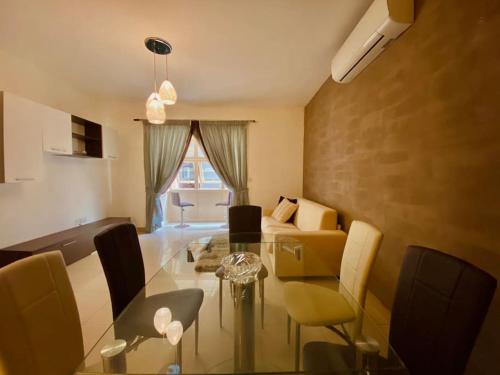 uma sala de estar com uma mesa de vidro e um sofá em Good value for money - Close to D seafront & bars em Sliema