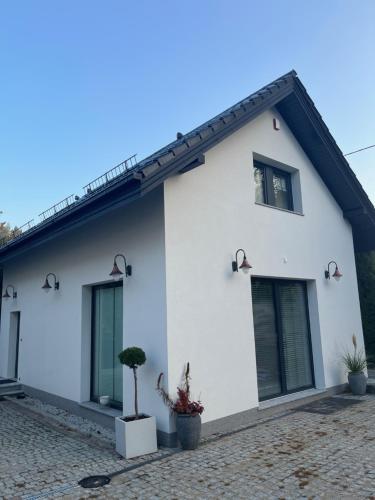 Biały dom z oknami i doniczkami w obiekcie Apartament Złoty 2 w mieście Cieciorka