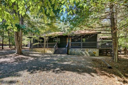 a log home with a large porch and trees at Private Broken Bow Cabin with Hot Tub and Gazebo! in Broken Bow