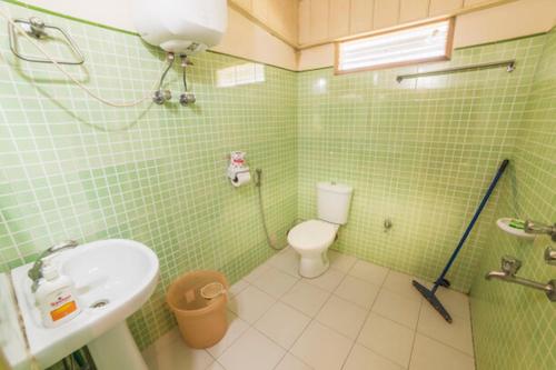 a green tiled bathroom with a sink and a toilet at Yangsum Heritage Farm in Rinchingpong