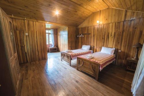 a room with two beds in a wooden cabin at Yangsum Heritage Farm in Rinchingpong