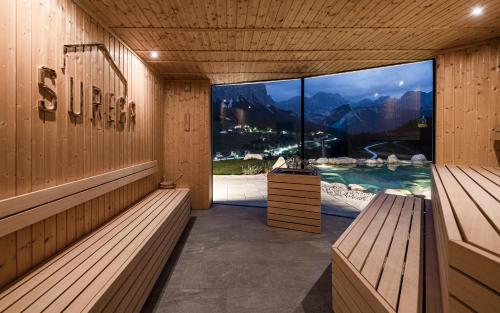 a sauna with two benches and a large window at Surega - Idyllic Farmhouse in San Cassiano