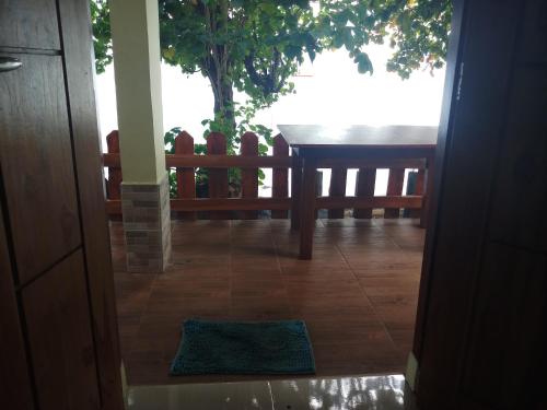 una porta aperta su un portico con tavolo e panca di Lena house Flores a Hitokalak