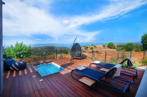 a deck with a swimming pool and chairs on it at Dimeli - Sea View Villas in Foinikounta in Finikounta