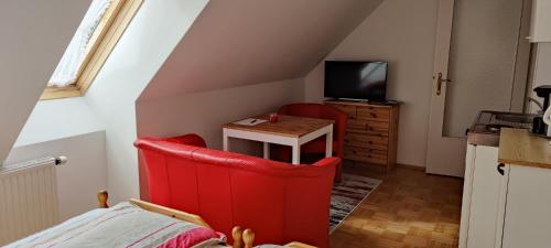 a room with a red chair and a table and a television at Haus Elsasser in Sankt Johann am Tauern