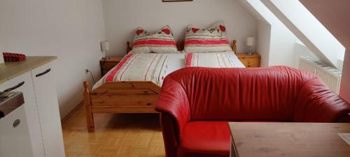 a bedroom with a bed and a red chair at Haus Elsasser in Sankt Johann am Tauern