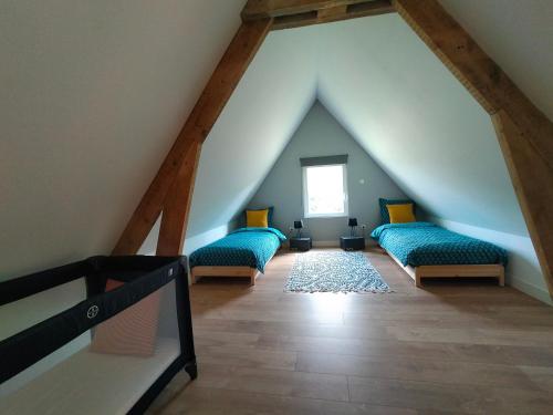a attic room with green couches and a window at Le domaine des biches in Longueville