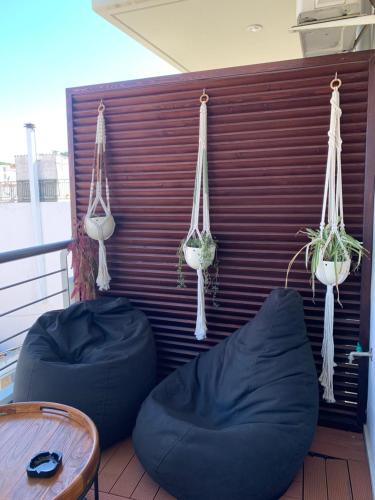 un balcón con 2 sillas y plantas con pufs en The Grey Apartments, en Volos
