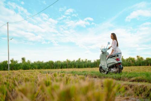 a woman is riding a scooter in a field at Skyspace Villas Bali in Dalung