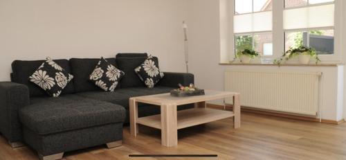 Sala de estar con sofá negro y mesa de centro en Seestern, en Greetsiel