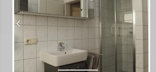 een badkamer met een wastafel en een glazen douche bij Seestern in Greetsiel