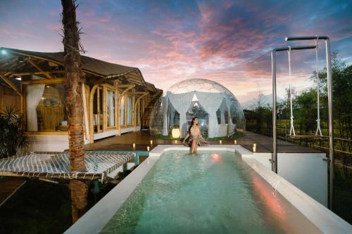 a woman standing in a swimming pool next to a house at Skyspace Villas Bali in Dalung