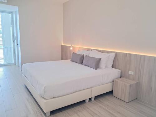a white bedroom with a white bed with pillows at WIIN Phetchaburi วิน เพชรบุรี in Phetchaburi