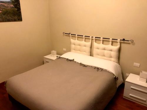 Schlafzimmer mit einem Bett mit weißer Bettwäsche und Kissen in der Unterkunft Didi House in Montepulciano