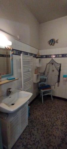 a bathroom with a sink and a chair at Résidence LE11B in Uzerche