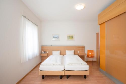 um quarto com uma cama com lençóis brancos em Hotel-Restaurant Eyholz em Visp