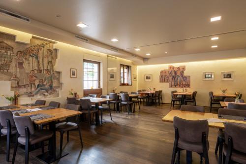 um restaurante com mesas e cadeiras e pinturas nas paredes em Hotel-Restaurant Eyholz em Visp